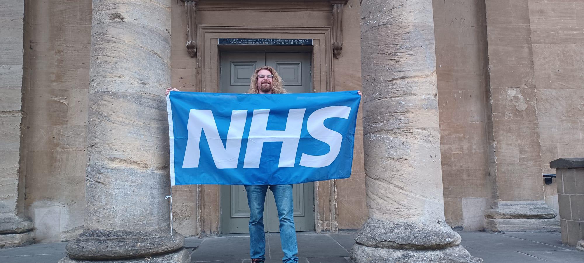 Cllr Ben Bibby holding the NHS flag 